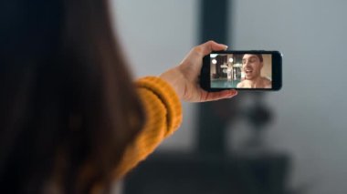 Bir kadın, erkek arkadaşıyla telefon görüşmesini videoya kaydediyor. Neşeli çift internette web kamerasıyla sohbet ediyor. Evde cep telefonu tutan tanınmamış kız elleri. Video konferansında iletişim kuran mutlu arkadaşlar