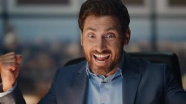 Kapanışta mutlu iş adamı gece ofisinde başarıyı kutluyor. Neşeli erkek çalışan, karanlık işyerinde iyi haberler alıyor. Gülümseyen sakallı adam akşam iş yerinde evet hareketi yapıyor. 