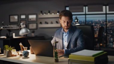 Düşünceli adam gece kabinesinde akıllı telefon ihbarını kontrol ediyor. Odaklanmış patron panoramik karanlık ofiste cep telefonu haberleri okuyor. Akıllı yönetmen bilgisayar işyerinde cep telefonu ekranı arıyor