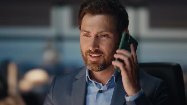 有胡子的男子在深夜接公司办公室的电话 笑着说手机的男人在晚上的室内听到好消息会做出反应 积极的生意人在黑暗的工作场所与朋友聊天 — 图库视频影像