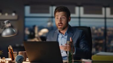 Heyecanlı iş adamı, müşterileri karanlık ofiste otururken çevrimiçi toplantıda açıklıyor. Başarılı duygusal adam video görüşmesiyle kontratı tamamlıyor. Masada el kol hareketi yapan zarif bir patron.