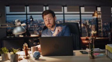 Tükenmiş yönetici, gece ofisindeki bilgisayar işyerinde kahve içiyor. Çok çalışan iş adamı çayını yudumlarken iş yerinde dizüstü bilgisayar görüntüsü izliyor. Lamba lambasında çalışan yorgun adam sorunları çözüyor. 
