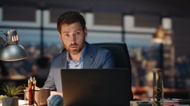 Gece görüş ofisinde iş adamı görüntülü sohbet dizüstü bilgisayarı. Müşteri sanal konferansında notlar alan odaklanmış bir adam. Ciddi bir erkek patron tek başına bilgisayarla iletişim kuruyor. 