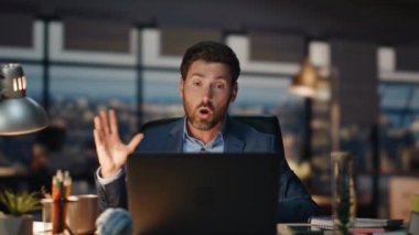 Sinirli adam akşam iç mekanda video görüşmesini tartışıyor. Duygusal olarak rahatsız olan yönetmen bilgisayardaki görüntülü sohbette el kol hareketi yapıyor. Sinirli iş adamı geceleri bilgisayarın sesini yükseltiyor.