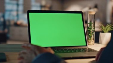 Yakından bir iş adamı, gece ofisindeki yeşil ekran bilgisayarına video çağrısı yapıyor. Tanımlanamayan patron dijital cihaz yakınlaştırması kullanıyor. Krom anahtar dizüstü bilgisayara el kol hareketi yapan bir erkek. 