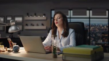 Stresli bayan gece geç saatlerde ofiste fazla mesai yaptığı için baş ağrısı çekiyor. Yorgun iş kadını dizüstü bilgisayar okumaya odaklanmıştı. Esmer kadın migren ağrısı çekiyor. 