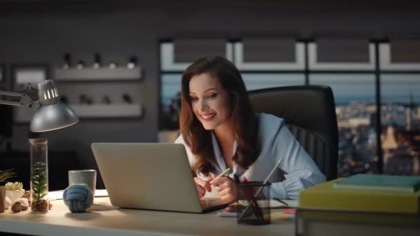 ナイトビューオフィスでラップトップビデオチャットを持っているボス 笑顔の女性は 肯定的な顔でクライアント仮想会議を話します キャビネットでコンピュータビデオコールを通信するビジネスマンを笑う — ストック動画
