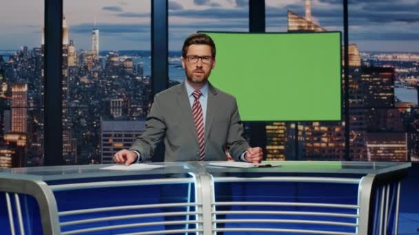テレビチャンネルスタジオでニュースを報道する緑色のスクリーンを示すプレゼンター エレガントなスーツのベアードニュースリーダーは クロマキーモニターに立っている毎日のイベントについて話します テレビ業界のコンセプト — ストック動画