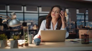 Karanlık ofisteki hayal kırıklığına uğramış iş kadını. Üzgün şef dizüstü bilgisayar ekranı panoramik pencere acentesinde yüz hareketi yapıyor. Üzgün bir bayan iş problemlerinde tepki gösteriyor. 