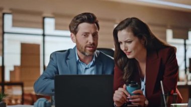 İş ortakları, aydınlık ofis kapanışında beş profesyonel başarı kutluyor. Olumlu gülen adam kadın meslektaşlar geniş kabinede dizüstü bilgisayar projesini tartışıyorlar.