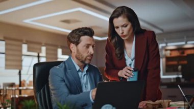 Laptop masasında yönetici ofis asistanı. Yakın plan. Kahve yudumlayan düşünceli bir kadın toplantı odasında erkek arkadaşını dinliyor. İş çifti birlikte bilgisayar izleme planlarını tartışıyor.