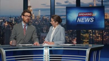 Şık haber spikerleri akşam televizyon programında son dakika haberlerini sunuyor. Ciddi profesyonel sunucular haber yayınına başlıyor. İş etkinliği hakkında kendinden emin sunucular