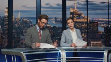 Profesyonel televizyon sunucuları akşam haberlerini modern stüdyonun kapanışında konuşuyorlar. Haber odasında haber bültenlerini birlikte sunan kendine güvenen spikerler. Seçkin çift günlük olaylara ev sahipliği yapıyor
