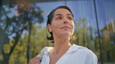 Gülümseyen iş kadını şehir merkezindeki binalara yakından bakıyor. Başarılı yetişkin CEO 'su Summer City' de kariyer başarısının tadını çıkarıyor. Mutlu lider kadın modern ofis bölgesinde tek başına dinleniyor.