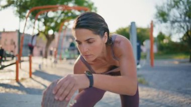 Şehir stadyumunda bacaklarını ısıtan atletik bir kadın. Orta yaşlı koşucu, açık havada esneme hareketleri yaparak vurgun yapıyor. Formda bir bayan kaslarını çalıştırıyor dışarıda koşuya hazırlanıyor. 