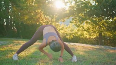 Spor kadın güneş ışınları parkında viraj yapıyor. Esnek atlet kadın yeşillik doğasında kaslarını ısıtıyor. Orta yaşlı sporcu kadın tek başına koşmaya hazırlanıyor.