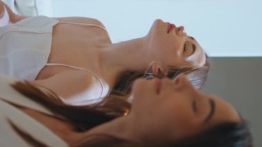 Meditasyon grubu sıcak bir odada yoga pratiği yapıyor. Sınıfın dikey görünümünde aroma yakan sakin kız. Lotus pozisyonunda meditasyon yapan kadınlar. Sakin arkadaşlar farkındalık egzersizlerinin tadını çıkarıyorlar.