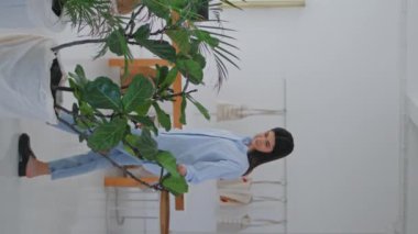 Modern iş merkezinde yürüyen bir kız. Tasarım mağazası ziyaretçisi haftasonu dikey manzaralı sergiden hoşlanan yeşil bitkilere bakıyor. Çağdaş müzede beyaz koridora çıkan sakin kadın.