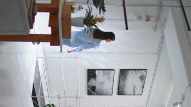 Çağdaş sanat galerisini ziyaret eden bir kadın. Rahat kız, müzenin dikey videosunun keyfini çıkarıyor. Tanımlanamayan esmer görünümlü sanat eseri kurulumu. İşçi modern ofiste mola verdi.