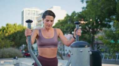 Yaz sokağı kapanışında eliptik makine eğiten mutlu bir sporcu. Formda, formda bir kadın. Yeşillik şehrinde tebessümle yürüyüş yaparak spor yapıyor. Kilo kaybı aerobik kavramı 