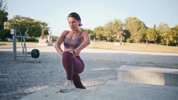 在城市体育馆里柔韧的女人伸展腿 在夏季城市进行健身锻炼时 穿着运动服的自信女士正在热身 中年妇女准备独自在露天地方慢跑 — 图库视频影像