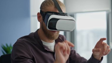 VR teknolojilerini yakından inceleyen ilham verici bir adam. Kulaklıklı oyun tasarımcısı ofisin parlak iç çekimlerinde arttırılmış gerçeklik üzerinde çalışıyor. Yaratıcı uzman sadece 3D programı test ediyor. Yüksek teknoloji konsepti 