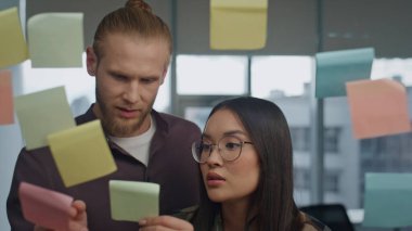 Arkadaş canlısı meslektaşlar ofis portresindeki cam panoyu tartışıyorlar. Uzak bir iş yerindeki komik kadının alnına çıkartma yapıştıran olumlu bir adam. Gülen çift şeffaf duvar toplantı odasında eğleniyor.