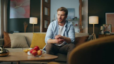 Kafası karışık adam kanepeyi içeride düşünüyor. Evdeki sorunları düşünen düşünceli bir erkek. Odaklanmış yeni başlayanlar için iş çözümleri. İş yerinde fikir arayan yakışıklı bir adam.