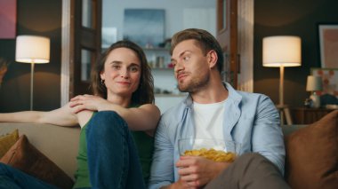 Gülümseyen bir çift hafta sonu evde gülüyor. Heyecanlı mutlu eşler komedi filmi izlerken yan yana oturup zum yapıyorlar. Kaygısız pozitif çift akşam yemeğinde atıştırmalıkların tadını çıkarıyor.