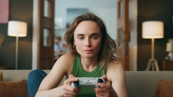 Pov focused player gaming controller at home. Young serious woman holding joystick playing car racing games alone at living room zoom on. Involved millennial girl enjoying console videogame closeup