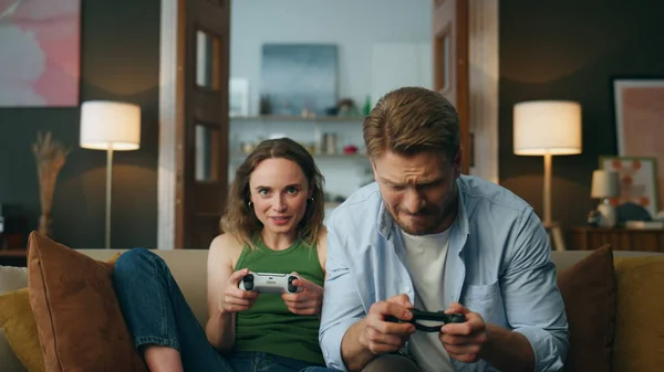 Pov couple playing console game at evening house. Excited active pair holding controllers trying win in video game zoom on. Nervous man smiling woman enjoying competition spending free time together