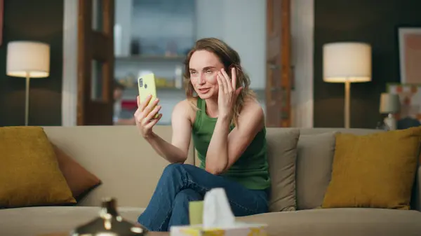Artistic woman speaking phone video call at home. Relaxed lady laying sofa gesticulates theatrically. Smiling blogger recording smartphone content holding gadget. Girl sitting couch at lazy weekend