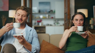 Dinlenen eşler kanepede çay içerken yakınlaşırlar. Aşk çifti sabah kahve fincanlarının keyfini çıkarıyor. Sakin koca eşi bej koltukta sıcak bir içecek yudumluyor. İnsanlar ev yaşam tarzı konsepti