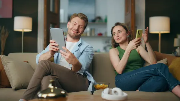 집안에 태블릿을 가리키는 남편이야 농담에 반응하는 다루기 소파에서 전화를 친구와 — 스톡 사진