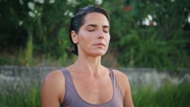 Green Park 'ta meditasyon yapan sakin bir Yogi kadını. Kapalı gözlü sporcu kadın derin derin nefes alıp dikkatli çalışmalardan zevk alıyor. Çekici bir bayan yaz doğasında dinleniyor nefes egzersizleri yapıyor.