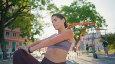 Güneş Stadyumu 'nda esnek antrenman yapan güçlü bir bayan. Yaz şehrinde ısınmak için bacaklarını açan ciddi sporcu kadın. Spor hocası kadın temiz havada antrenman yapıyor. Sağlıklı yaşam tarzı