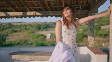 Güneş ışınları bahçesinde çamaşır tutan rahat bir model. Rüzgarlı, şehvetli, mesafeli bir kadın dağ manzaralı terasta ev hayatını rahatlatıyor. Nazik baştan çıkarıcı bayan dışarıda yalnız dinleniyor.