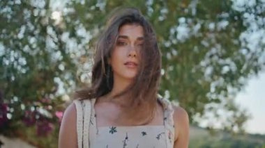 Ağaçlara yeşil arka plan portresi çizen kadın. Çekici seksi kız rüzgarlı saçlara dokunuyor yaz parkında dinleniyor. Güzel bayan kırsal alanda dinleniyor. Huzurlu sakin insanlar konsepti 