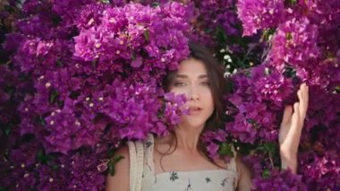 Çiçekli portre narin bayan yazın doğasına poz veriyor. Seksi model çiçek bahçesinde dinleniyor. Kamera baştan çıkarıcı bir şekilde yakın çekim yapıyor. Güzel bir kadın tatilde hafif esintinin tadını çıkarıyor. Hafta sonlarını sakin geçiren kız