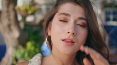 Portre romantik model gülümseyen kamera bulanık doğa arka planında. Mutlu kadın yüzü yaz rüzgârının tadını çıkarırken objektife yakından bakıyor. Kırsal bölgede poz veren hassas bir kadın. Rahat kız saçı