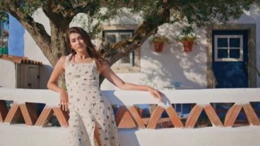 Gülümseyen kadın güneş ışığı köyü portresi yapıyor. Dişi mutlu model Akdeniz 'deki evleri dinlendiriyor. Çekici güzel kız kameraya bakıyor ve rüzgarın tadını çıkarıyor. Şefkatli esmer kadın yalnız başına dinleniyor.