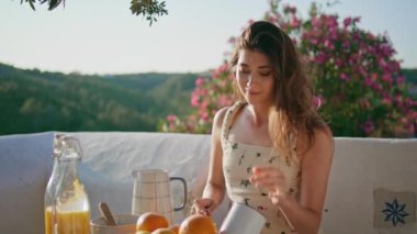 Gülümseyen kadın tek başına yemek pişiriyor açık hava balkonuna elma koyuyor. Romantik kız tek başına sağlıklı bir kahvaltı hazırlıyor. Güzel model, sakin bir hafta sonu tatili.
