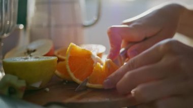 Güneşli terasta elinde bıçakla narenciye doğrayan kadın elleri. Tanınmayan bir kadın temiz havada portakal kesiyor. Anonim model yaz balkonunda yemek hazırlıyor.