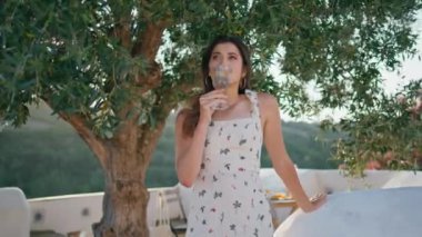 Doğa manzaralı terasta limonata içip eğlenen son model. Romantik bir bayan sadece meyveli su içiyor. Nazik kadın soğuk sıvı yudumluyor balkonda rüzgarı hissediyor