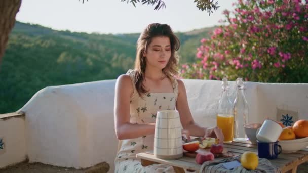 テラスのクローズアップでフルーツをカットロマンチックな女性 ブルネットの女性は 夏の山の景色の場所で朝食を楽しんでリンゴを食べています 独りで夢を見る自由な時間を費やす優しい女性モデル — ストック動画