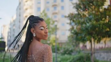 Yeşil sokak portresi üzerinde yürüyen afro-amerikan kadın. Moda özgüvenli model kamera örgülere yakından dokunuyor. Gülümseyen siyah saçlı kadın sokakta tek başına dolaşıyor. Moda kız yaşam tarzı. 