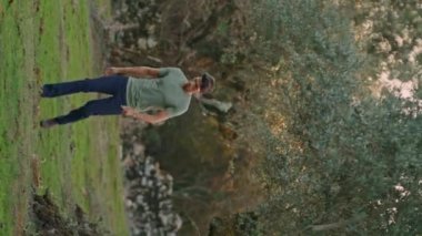 Ciddi bir çiftçi zeytin çiftliğinde yürüyor. Yaz akşamı kırsal kesimde dikey videoda odaklanmış bir işçi karşıya geçiyor. Adam hasattan sonra sepeti kontrol ediyor. Düşünceli bahçıvan kırsal alanda çalışma yapıyor.