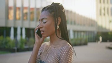 Siyah saçlı kadın Sundown City caddesinde tek başına cep telefonunu arıyor. Afro-Amerikan bayan ofis binasının yakınında telefon görüşmesi yapıyor. Akıllı telefondan konuşan çekici moda kızı.