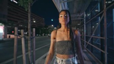 Çekici bir kadın, gece yarısı şehrine gelip seksi bir portrede poz veriyor. Çekici genç model demir yapıya dokunuyor. Kameraya yakından bakıyor. Kendine güvenen şehvetli kız akşamın tadını çıkarıyor. Moda konsepti 
