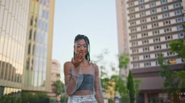 Romantik esmer, moda düşkünü, flört eden kameralar akşam kare resimlerinde geziniyor. Günbatımında şık kıyafetli Afro saçlı kadın yürüyor. Çekici seksi kadın eğlence alanında el pozu veriyor.